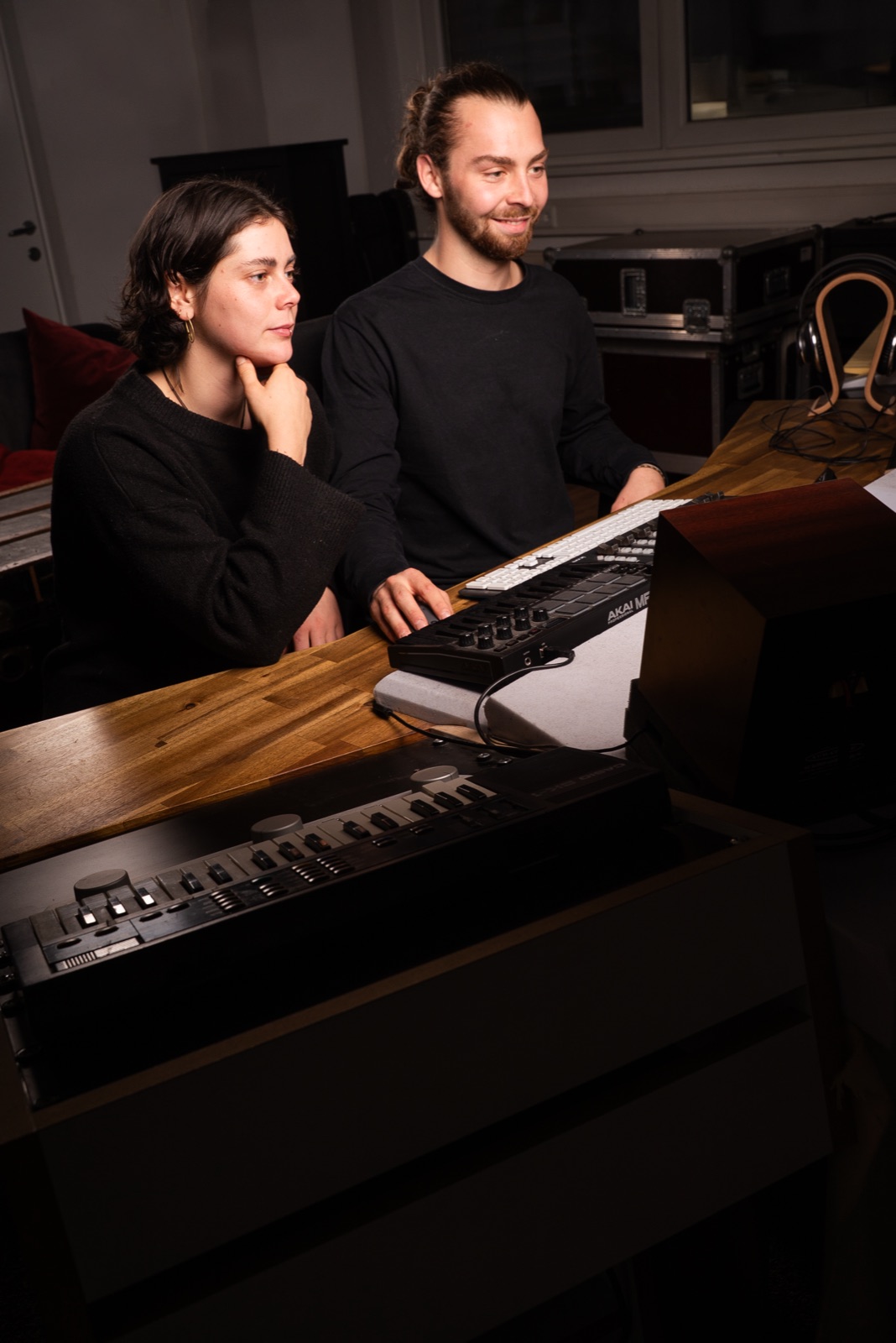 Two producers working on a synthesizer